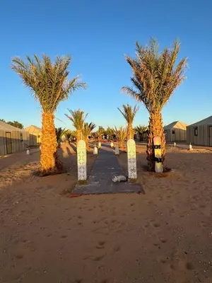 a path between two palm trees in the desert at Erg Chebbi Sahara Camp in Merzouga