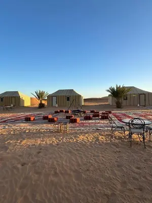 a group of benches sitting on the sand in the desert at Erg Chebbi Sahara Camp in Merzouga