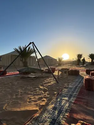 a large object in the desert with the sunset in the background at Erg Chebbi Sahara Camp in Merzouga