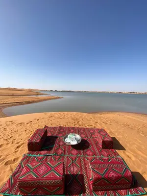 a table on the sand in front of a body of water at Erg Chebbi Sahara Camp in Merzouga