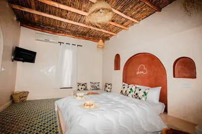 a bedroom with a large white bed with two animals on it at Aghmat Lodge Guest house in Marrakech