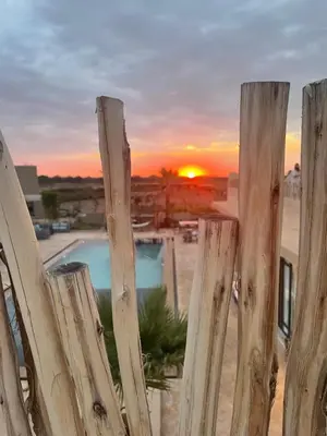 a wooden fence with a sunset in the background at Aghmat Lodge Guest house in Marrakech