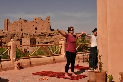 a man and a woman doing yoga in front of a castle at Bab El Atlas in Kalaat MGouna