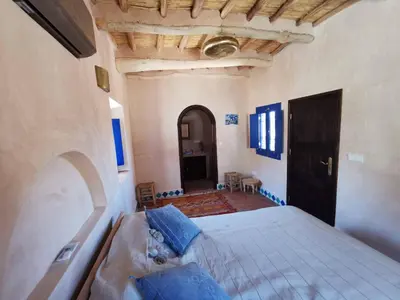a bedroom with a large bed with blue pillows at Bab El Atlas in Kalaat MGouna