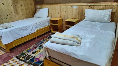 two beds in a room with wooden walls at GITE BOUKHALFA in Missour