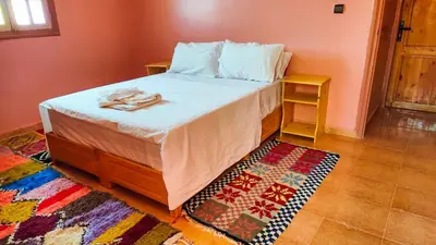 a bedroom with a bed and a rug on the floor at GITE BOUKHALFA in Missour