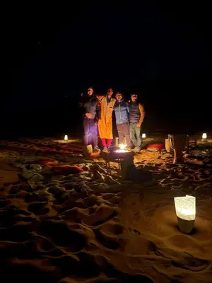 a group of people standing around a fire on a beach at Gambi Camp in Hassilabied