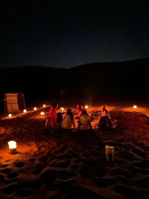 a group of people sitting on a beach at night at Gambi Camp in Hassilabied