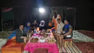 a group of people sitting around a table with food at Gambi Camp in Hassilabied