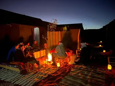 a group of people sitting around a fire in a tent at Gambi Camp in Hassilabied