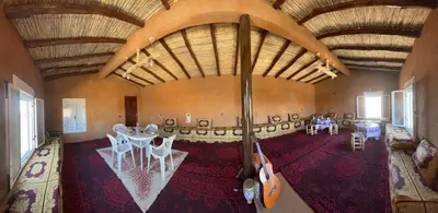 a room with a table and chairs and a guitar at Auberge camping café restaurant Relax Tazoulait in Bou Dib