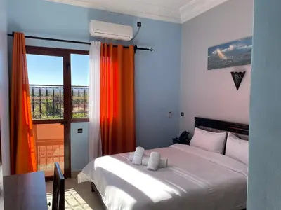 a bedroom with a white bed and a window at Hotel Rayyan l 'Escale in Ouarzazate