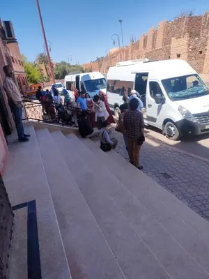 a group of people standing on a sidewalk next to vehicles at Hotel Rayyan l 'Escale in Ouarzazate