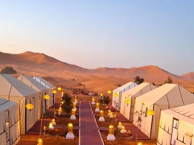 a row of white tents in the desert at nomad luxury camp in Merzouga
