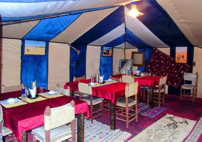 a dining room with tables and chairs in a tent at nomad luxury camp in Merzouga