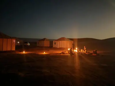 a group of people sitting around a camp fire at night at BiVOUAC CÔTE-IRIKI in Foum Zguid