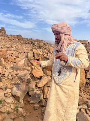 a man standing on rocks looking at his cell phone at BiVOUAC CÔTE-IRIKI in Foum Zguid