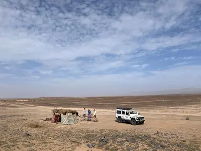 a group of people standing next to a jeep in the desert at BiVOUAC CÔTE-IRIKI in Foum Zguid