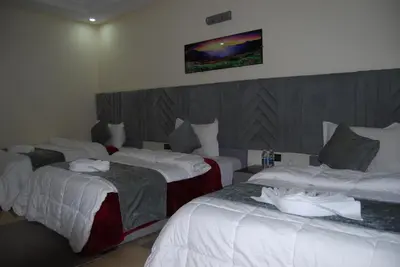 a hotel room with three beds and a tv on the wall at Hotel la Perle d'Arfoud in Erfoud