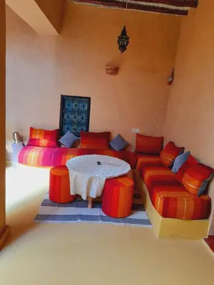 a room with two beds and a table and chairs at Gite d'étape nomade in Tajda