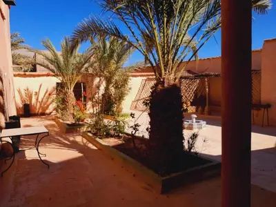 a courtyard with two palm trees and a table at Gite d'étape nomade in Tajda