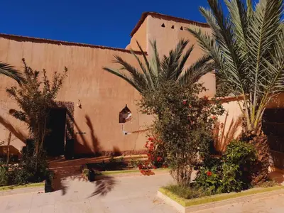 a building with palm trees in front of it at Gite d'étape nomade in Tajda