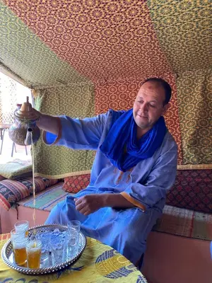 a man sitting at a table in a room at Gite d'étape nomade in Tajda
