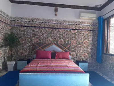 a bedroom with a bed with a wall covered in tiles at Riad Mini Batha Family Fez Chez ABBADI in Fès