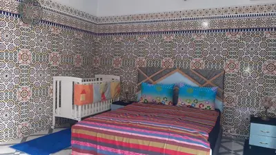 a bedroom with a bed in a room with wallpaper at Riad Mini Batha Family Fez Chez ABBADI in Fès
