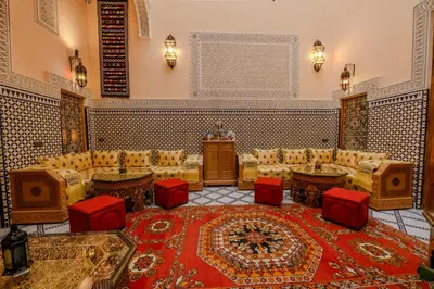 a living room with couches and red chairs and a rug at Riad Diamant De Fes in Fès