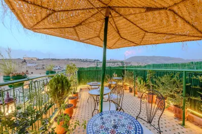 a balcony with tables and chairs and an umbrella at Riad Diamant De Fes in Fès