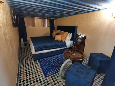 a bedroom with a bed and a couch and a table at Charmant appartement avec terrasse privee a fes medina in Fès