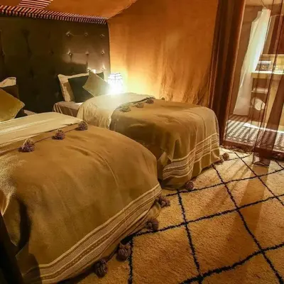 two beds sitting in a room with a window at Ahlam Luxury Camp in Merzouga