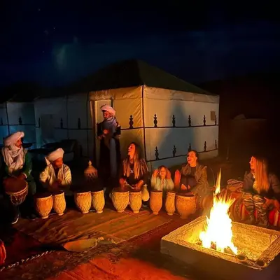 a group of people sitting around a fire at Ahlam Luxury Camp in Merzouga