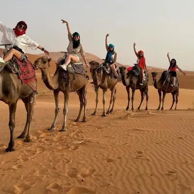 a group of people riding on camels in the desert at Ahlam Luxury Camp in Merzouga