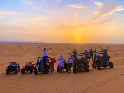 a group of people standing in the desert with atvs at Ahlam Luxury Camp in Merzouga