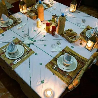 a table with a white table cloth with plates and glasses at Ahlam Luxury Camp in Merzouga