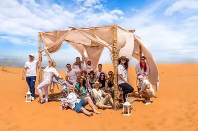 a group of people posing for a picture in the desert at Ahlam Luxury Camp in Merzouga