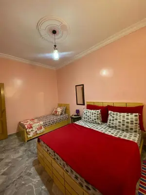 a bedroom with two beds in a room with pink walls at Le bel abri in Meknès