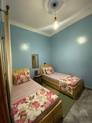 two beds in a room with blue walls at Le bel abri in Meknès