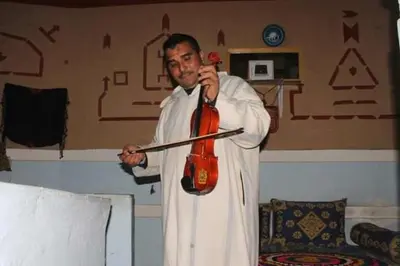 a man is talking on a phone while holding a guitar at Riad DAR outebba in Zaouïet Sidi Daoud