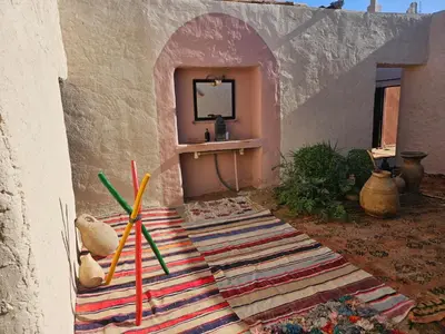 a room with a table with a mirror and a rug at LA PETITE MAISON DU LAC IRIKI in Foum Zguid