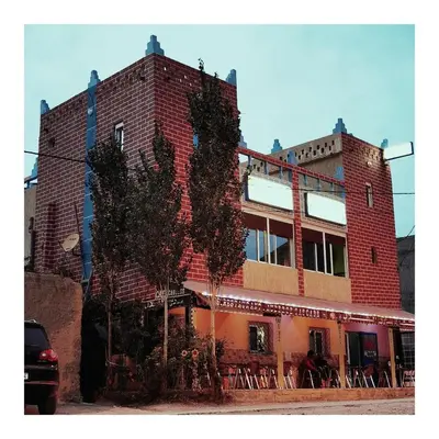 a red brick building with a tree in front of it at Auberge Cascade Imilchil in Imilchil