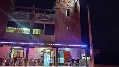 a brick building with blue lights in front of it at Auberge Cascade Imilchil in Imilchil