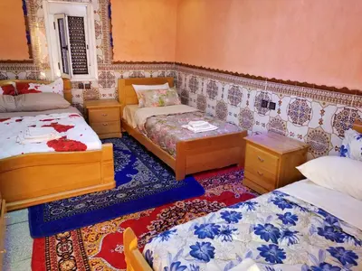 a room with two beds and two tables at Auberge Cascade Imilchil in Imilchil