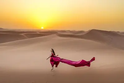 a woman in a dress running through the desert at Stargazing Merzouga Camp in Merzouga