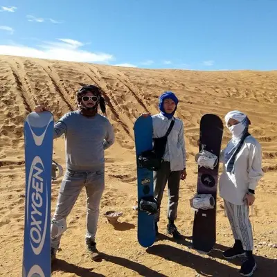 three men are standing with snowboards in the desert at Stargazing Merzouga Camp in Merzouga