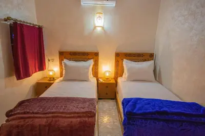two beds in a small room with a red window at Riad Fes Elite in Fès