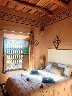 a bedroom with a large bed and a window at Maison d'hôtes IZZA in Kalaat MGouna