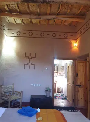 a bedroom with a bed and a chair in a room at Maison d'hôtes IZZA in Kalaat MGouna